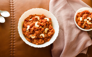 Gajar Halwa or Carrot Halwa is a traditional Indian dessert garnished with almond,raisins,nuts.Top view of Indian dessert or sweet made in winters,festivals-Diwali,Dussehra,Navratri in North India.