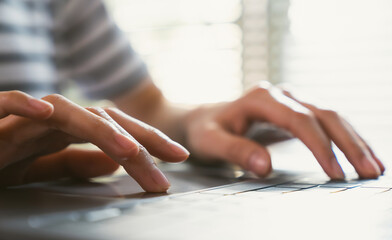 Hands typing keyboard on laptop with working online.