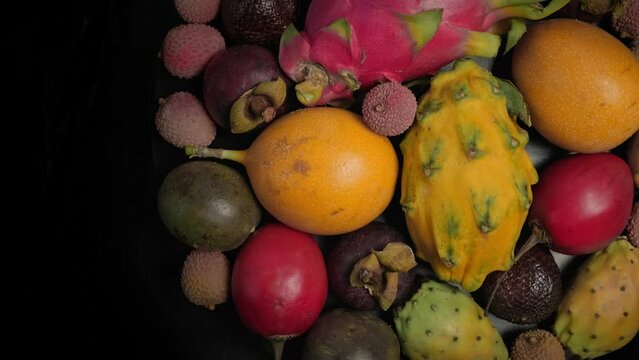 Exotic fruits rotation background. Passion fruit, Tamarillo, Lychee, Pitahaya, Salak, Granadilla, Mangosteen fruits in plate turning. Fresh tropical fruits rotate, close-up, top view, vertical video