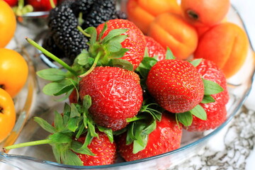 Bowl of fresh berries and cherries, apricots, strawberries, fruits, mulberries on a marble table.