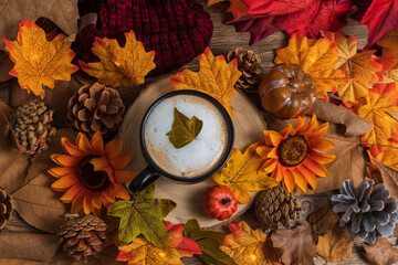 Cup of coffee with hat, leaves and pumpkins, autumn and halloween background from above
