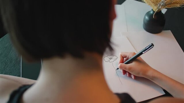 Tattoo master makes sketch of tattoo on paper. Artist drawing tattoo idea on paper in studio, woman working on future tattooing outline pattern