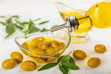 Olive oil in a bottle on a white texture background. Oil bottle with branches and fruits of olives....