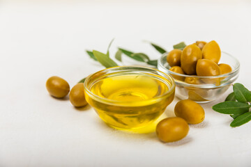 Olive oil in glass bowls, gravy boats and bottle on a textured kitchen table. Oil bottle with branches and fruits of olives. Place for text. copy space. cooking oil and salad dressing.Close-up.Flatley