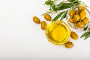 Olive oil in glass bowls, gravy boats and bottle on a textured kitchen table. Oil bottle with branches and fruits of olives. Place for text. copy space. cooking oil and salad dressing.Close-up.Flatley