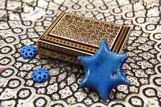 A wooden box of khatam with a blue ceramic star