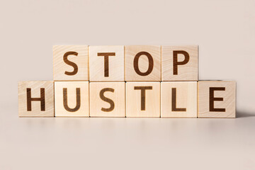 The word STOP HUSTLE on cubes on a beige studio background. Copy Space. Written. Text words matter....