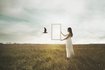 bird escaping through a surreal window held by a woman, concept of freedom - 651155735