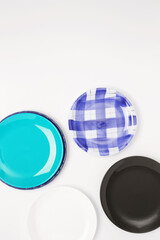 Multicolored dinner plates on a white background. Top view, copy space, flat lay