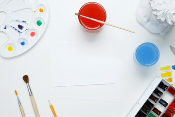 Watercolor and other artistic accessories on a white background. Artist's desk workplace. Top view, copy space, flatlay