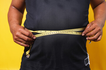 Fat man check out his body fat with measuring tape  - obrazy, fototapety, plakaty