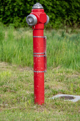 Fire hydrant in the field - red pipe with water in the Polish