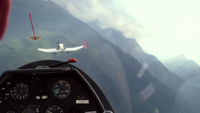 Glider towed at altitude by airplane between mountains and clouds