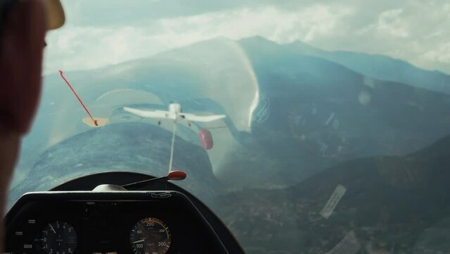 Glider towed at altitude by airplane between mountains and clouds