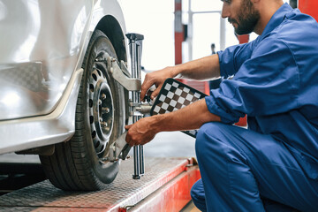 Taking care of wheel disk. Auto mechanic working in garage. Repair service
