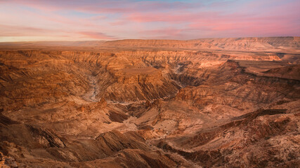 Panoramic view of Fish River Canyon in Southern Namibia, with impressive size and stunning geological formations. Captured at sunrise.