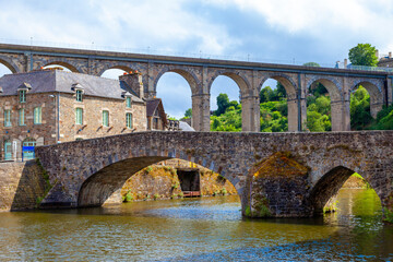 Fototapeta premium panoramic view of old stone bridge and historical medieval houses reflecting in La Rance river in Dinan town port