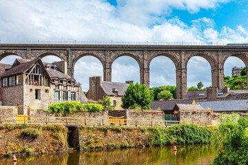 Fototapeta premium panoramic view of old stone bridge and historical medieval houses reflecting in La Rance river in Dinan town port
