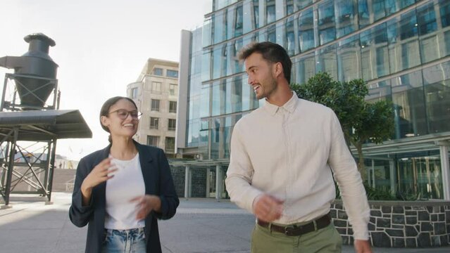 Young multiracial adults in businesswear talking next to office building in street