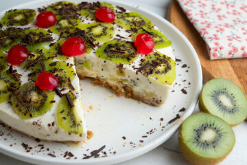 Yogurt and kiwi cake with a cookie base decorated with grated chocolate.