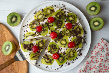Yogurt and kiwi cake with a cookie base decorated with grated chocolate.