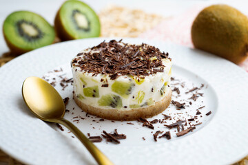 Yogurt and kiwi cake with a cookie base decorated with grated chocolate.