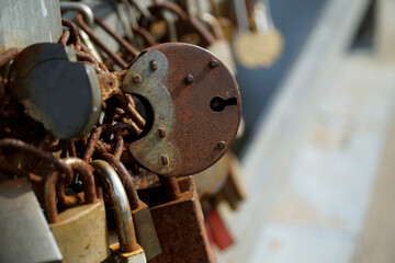 Many rusty padlocks closed on bridge fence - love concept