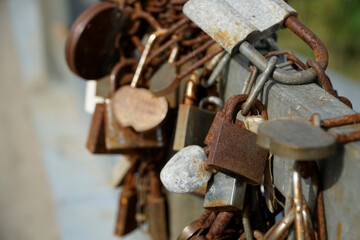 Many rusty padlocks closed on bridge fence - love concept