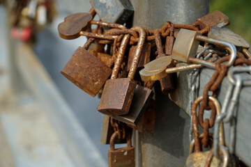 Many rusty padlocks closed on bridge fence - love concept