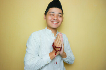 an Indonesian Muslim man of Asian descent wearing Muslim clothes and a black peci, celebrating Eid...