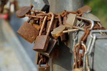Many rusty padlocks closed on bridge fence - love concept