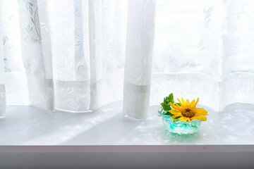 窓際に置かれた向日葵を生けた花瓶