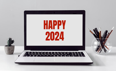 2024 with Happy New Year text on laptop screen on the workplace background
