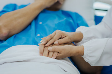 Fototapeta na wymiar Close-up shot of female nurse holding hands with her senior patient give support Doctor helping elderly patient A female attendant holds the hand of an elderly man