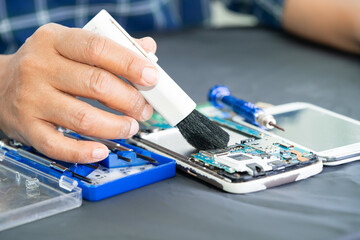 Asian technician repair and cleaning dirty micro circuit main board of smartphone electronic...