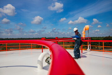 Male worker inspection at steel long pipes and pipe elbow in roof oil factory during refinery valve...