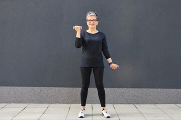 Mature woman in fashionable sportswear, exercising outdoors in an urban setting, showcasing health, beauty, and style.