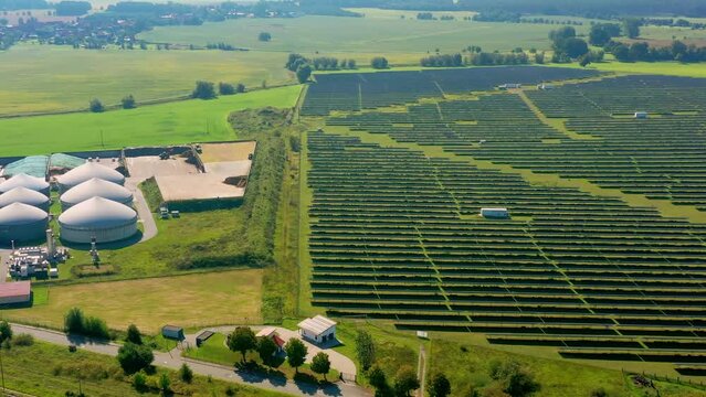 Aerial view of flight over a large field with solar panels to a biogas plant for generating electricity from methane in Germany