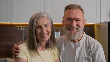 Retired Caucasian happy smiling married couple family gray haired grandma and grandpa wife and husband portrait middle-aged senior mature old man and woman in love hugging in kitchen health insurance