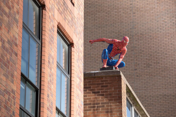 Naklejka premium Sheffield, United Kingdom - September 21, 2023: Life-size Spider-Man figure on the rooftop in Sheffield city centre.