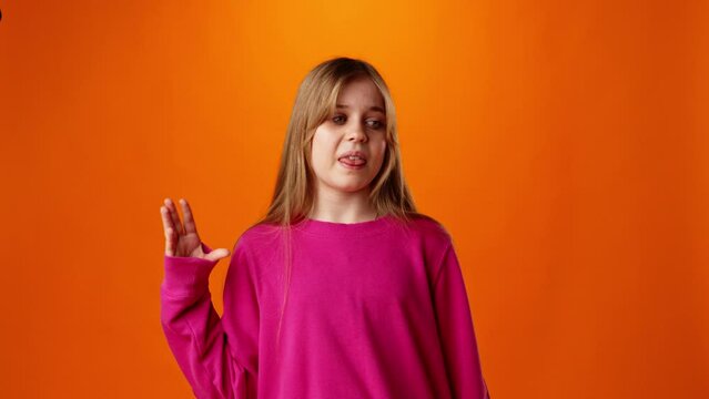 Teen girl showing bla-bla gesture against orange background in studio