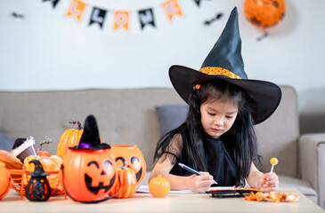 happy halloween. little girl draws a pumpkin and prepares to celebrate halloween at home