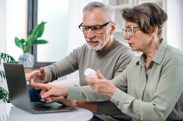 senior couple using laptop, buying medication together online - Powered by Adobe