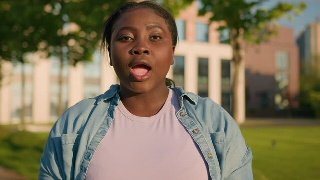 Oh my god wow amazed excited reaction African American funny plus size woman student girl surprise laugh news laughing looking camera with big eyes shocked close mouth with hands victory win outdoors