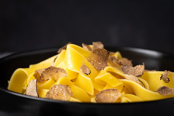 Tagliatelle pasta with black truffle mushrooms. Tagliatelle al tartufo - Italian autumn fresh recipe with black truffle, rustic dark style, macro. Autumn gourmet cuisine 