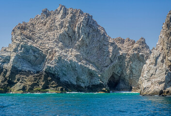 Fototapeta na wymiar Mexico, Cabo San Lucas - July 16, 2023: Closeup, cave, on Reserva de lobos Marinos, set in gray-beige rocky cliffs descending into greenish ocean water