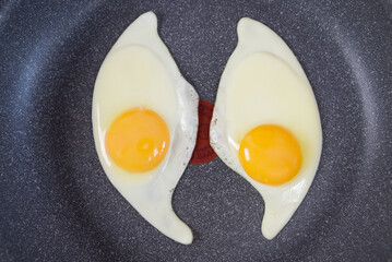 Two fried eggs in a frying pan isolated on white, top view