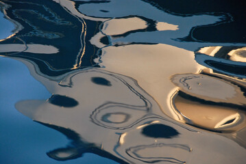 Reflections on water of sunlit moored boats, abstract background ideal for any artistic or commercial idea