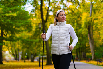 Nordic walking - woman exercising in city park
