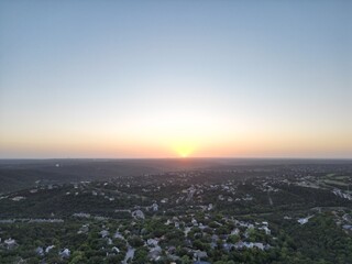 Obraz premium Sunset over the city and hill country. Clear blue skies. Orange sun. Vistas and panoramas.